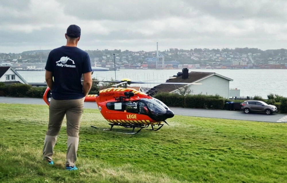 Foto: Mann med caps står med ryggen til og ser på et helikopter.