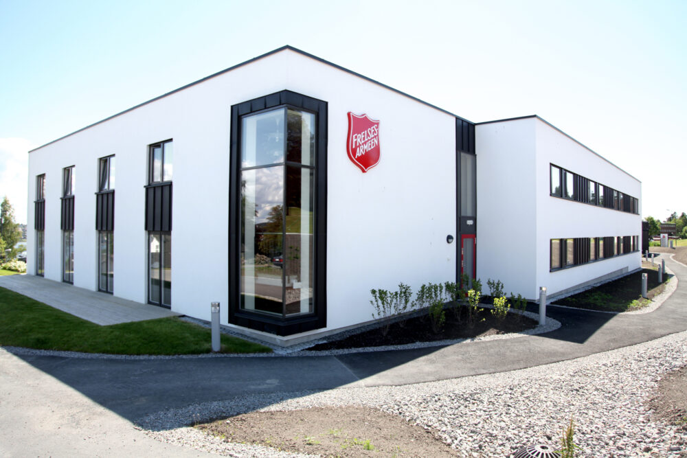 Foto: Hvitt, moderne funkisbygg sett fra hjørnet. Her er svarte vinduskarmer med ruter som går fra gulv til tak.