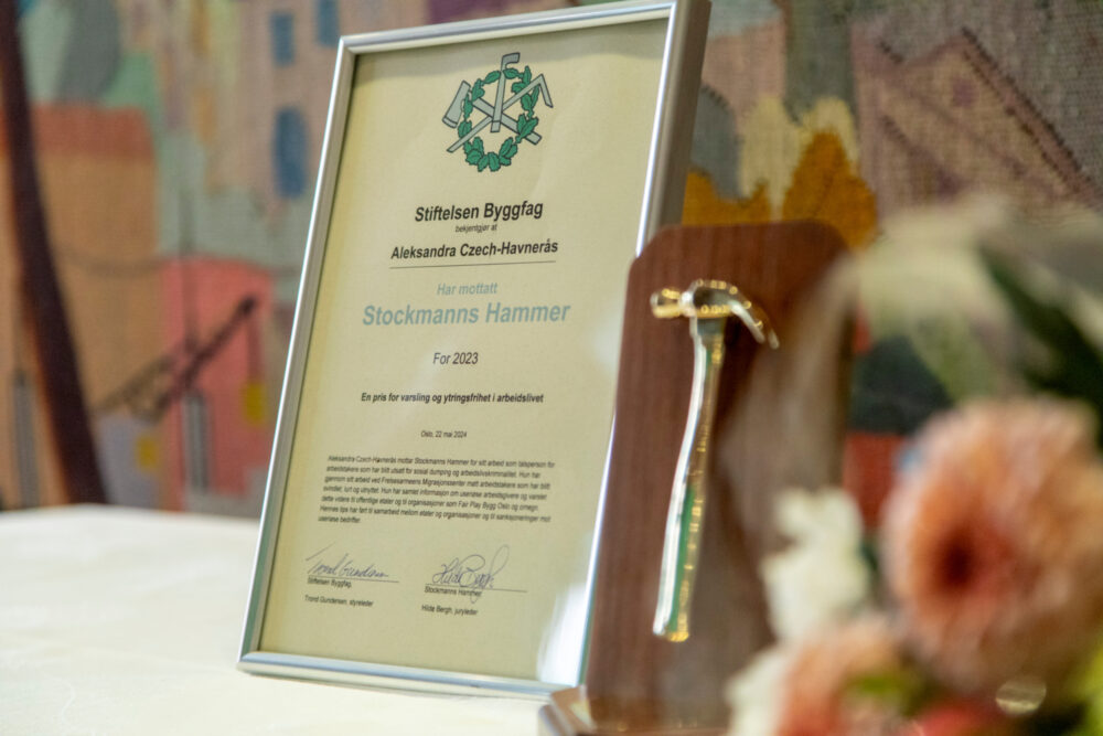 Foto: Nærbilde av et bord med hvit duk på. Der står diplomet i en ramme og prisen og blomsterbuketten ligger klar.