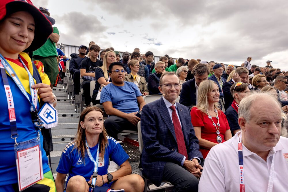Foto: Fra en tribune der folk sitter og står i fotballtøy og pentøy.