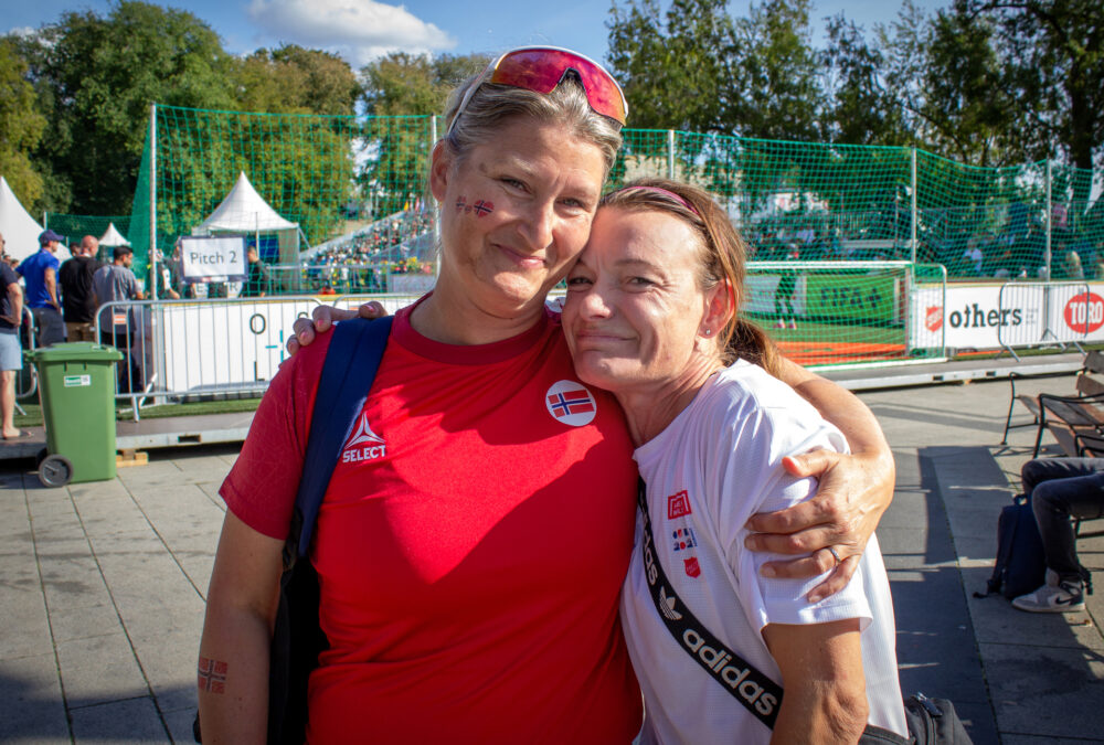 Foto: To kvinner står tett ved siden av hverandre og holder hardt rundt hverandre. Den ene har på seg rød fotball T-skjorte, den andre hvit.