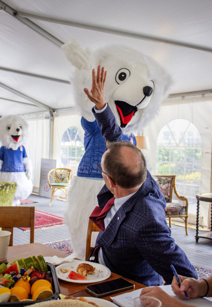 Foto: Mannen i dressen snur seg og gir high five til en hvit isbjørn-maskot.
