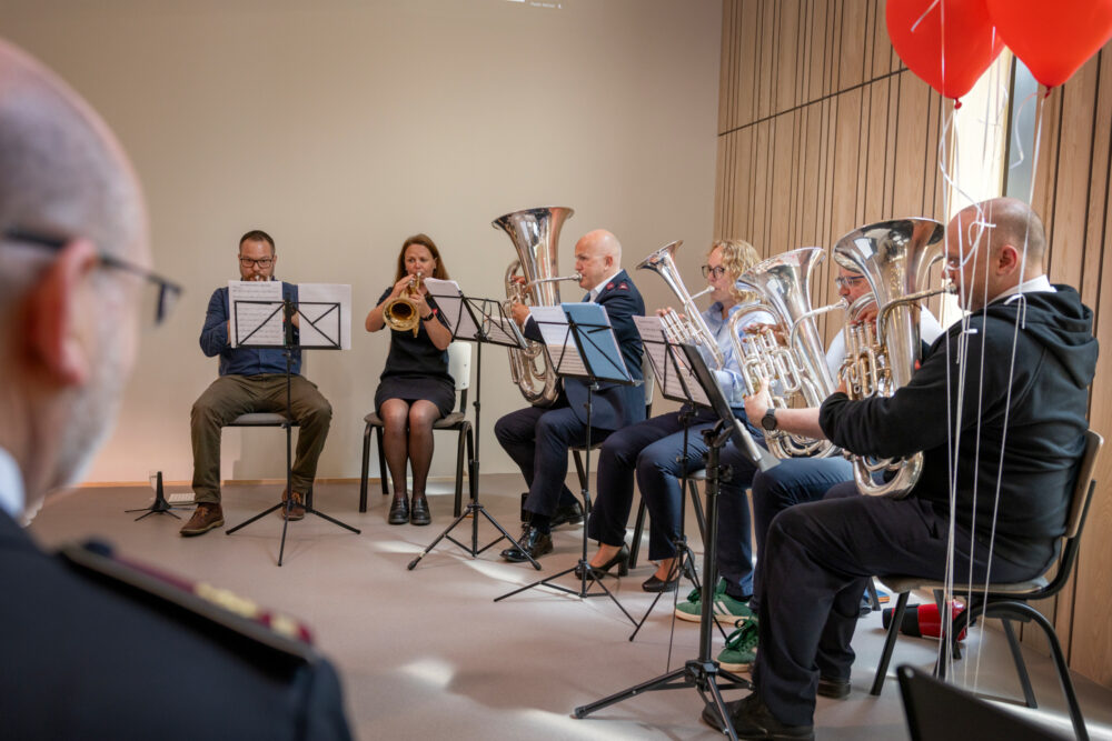 Foto: Seks stykker sitter og spiller hvert sitt brassinstrument.