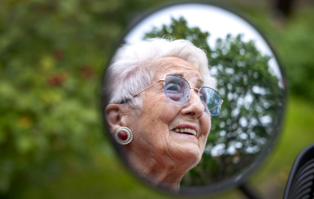 Foto: Tatt av en eldre kvinne i et rundt speil på et kjøretøy.