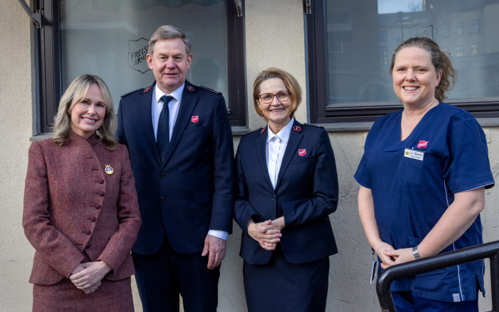 Foto: Fire personer oppstilt på rekke. Ekteparet i midten i uniform fra Frelsesarmeen. Kvinnen til høyre i blå sykehusklær.