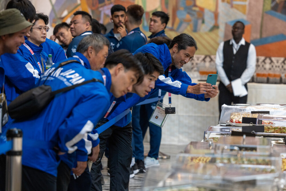 Foto: En gjeng med spillere fra Japan står på rekke og tar bilder av fingermaten på bordet.