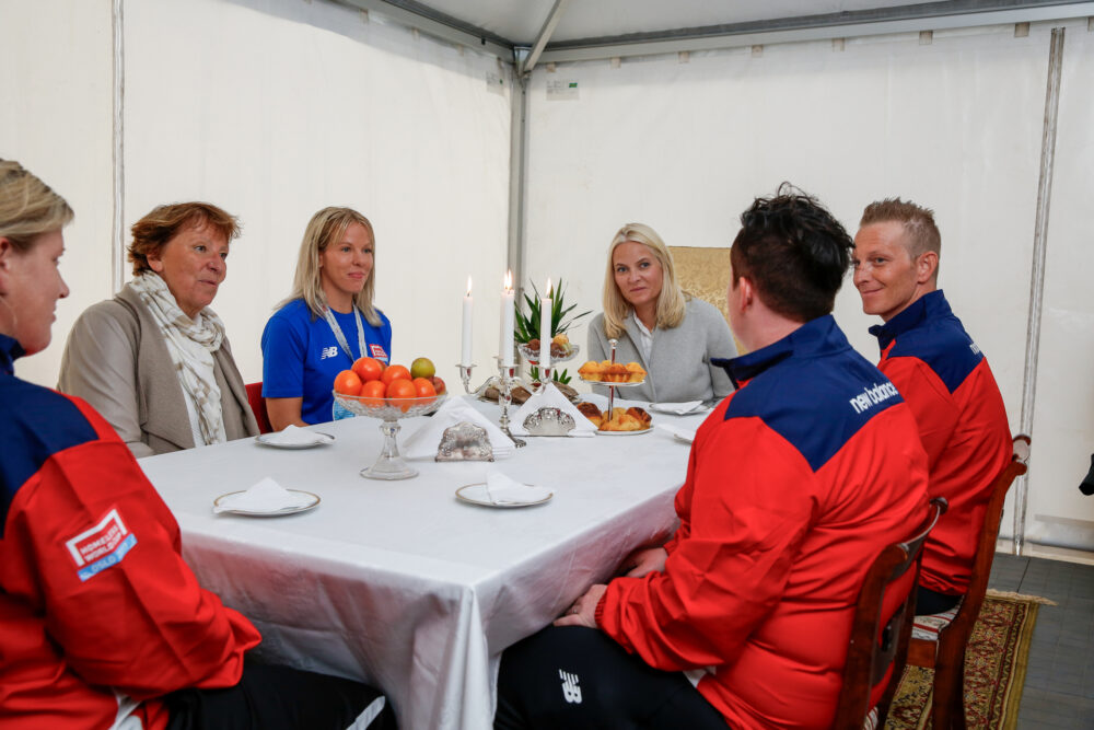 En gruppe mennesker sitter rundt et bord. Cathrine Johansen sitter mellom daværende Osloordfører Marianne Borgen, og H.K.H. Kronprinsesse Mette-Marit.