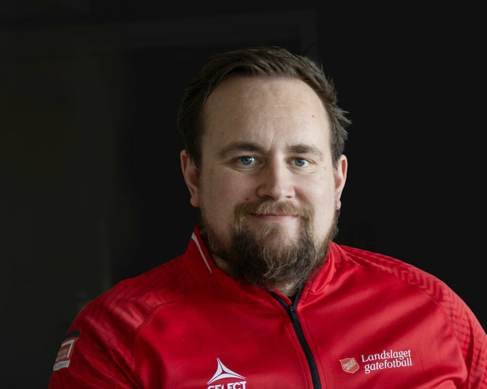 Mann i 30-årene med skjegg ikledd råd treningsjakke.