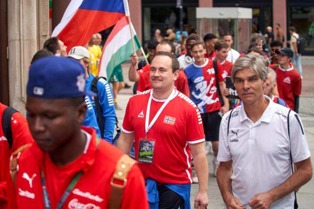 Mann i norsk landslagsdrakt i parade sammen med en rekke andre mennesker i ulike landslagsdrakter.