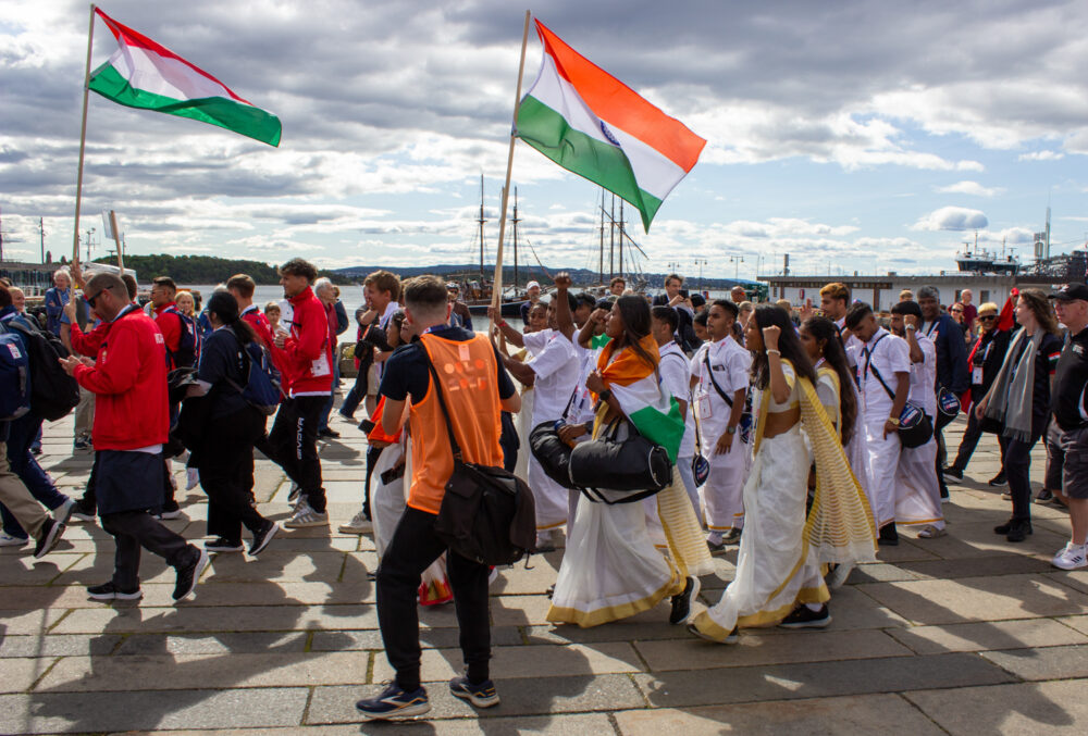 Foto: Mennesker i parade, de bærer flagg og har på seg både fotballdrakter og nasjonale drakter.