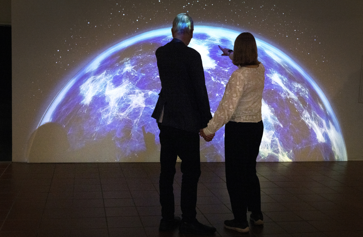 Foto: De samme to personene, far og datter, står med ryggen til kamera og peker på en skjerm bak som viser kloden.