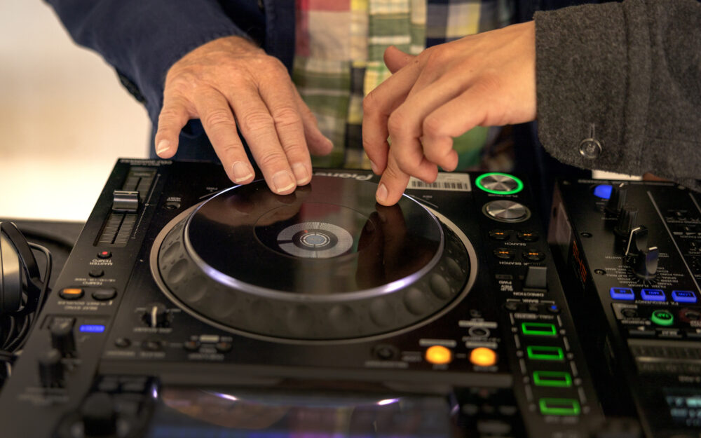 Foto: To ulike hender som begge snurrer på et hjul på en miksepult.