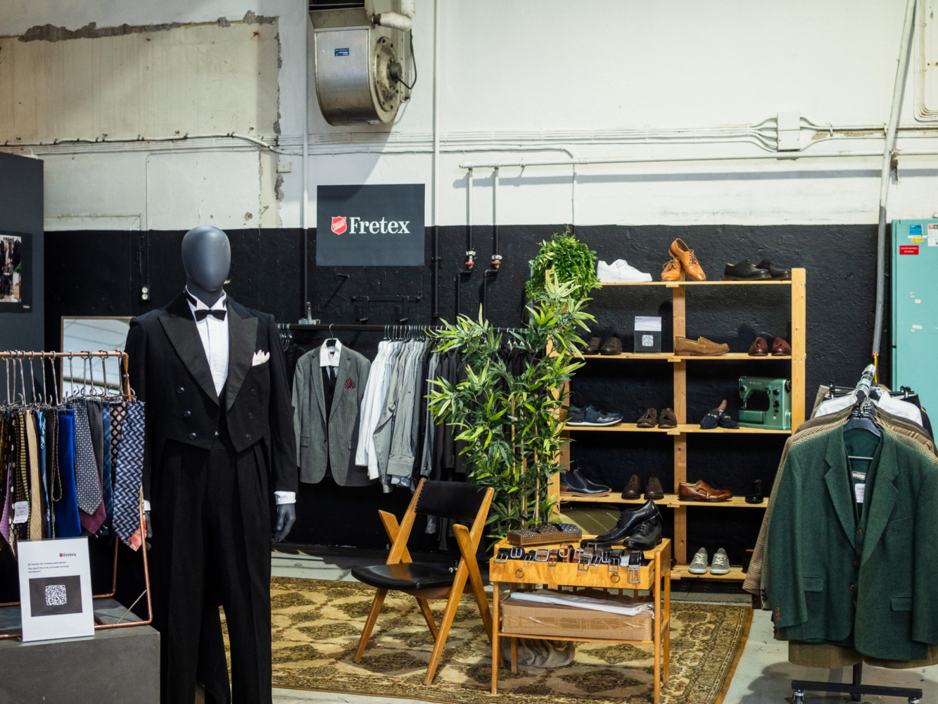 Et lokale i et industribygg der det er satt opp herreklær. I front en byste med dressjakke.