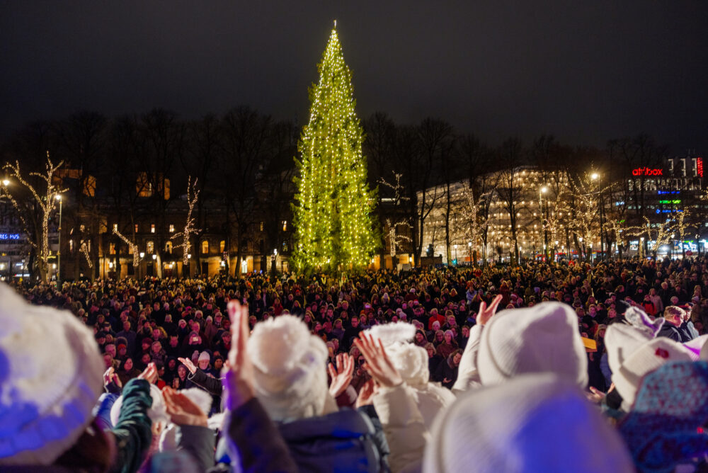 Foto: Det er mørkt ute og langt borte på en åpen plass fylt av mennesker, er lyser en diger julegran.