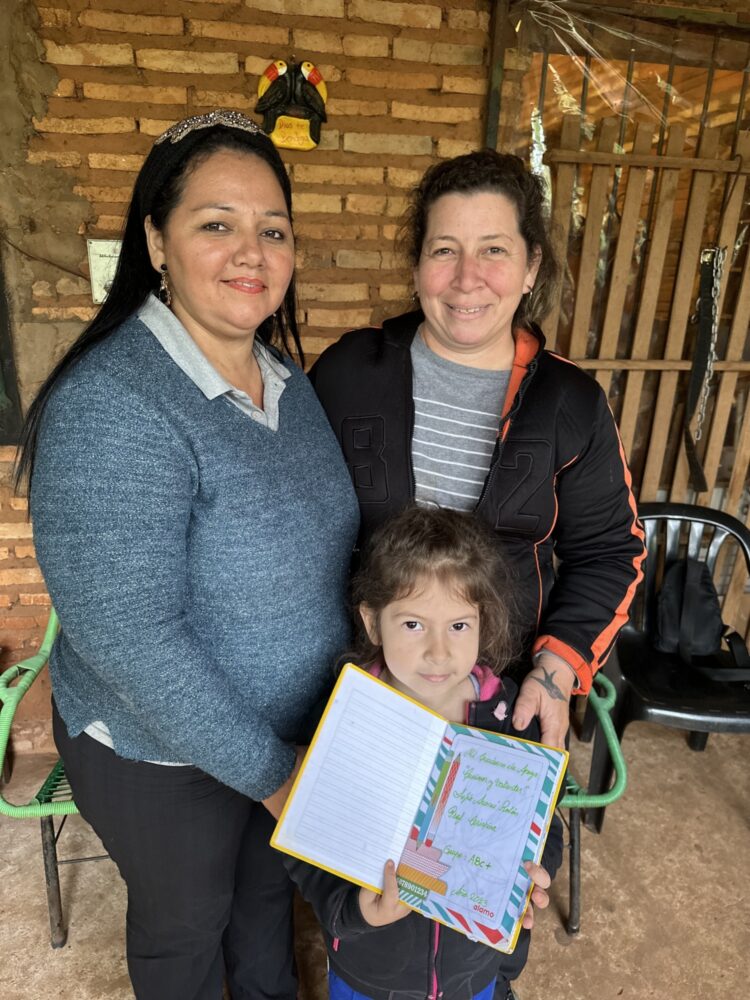 Foto: to kvinner og en jente der jenta viser frem lekseboka si