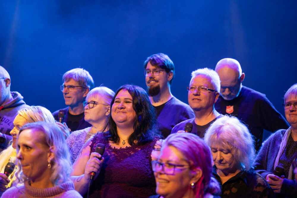 Foto: Et kor står oppstilt i rekker og det er med flest kvinner, men også noen menn.