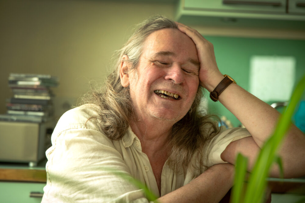 Foto: Mann med halvlangt hår ler hjertelig.