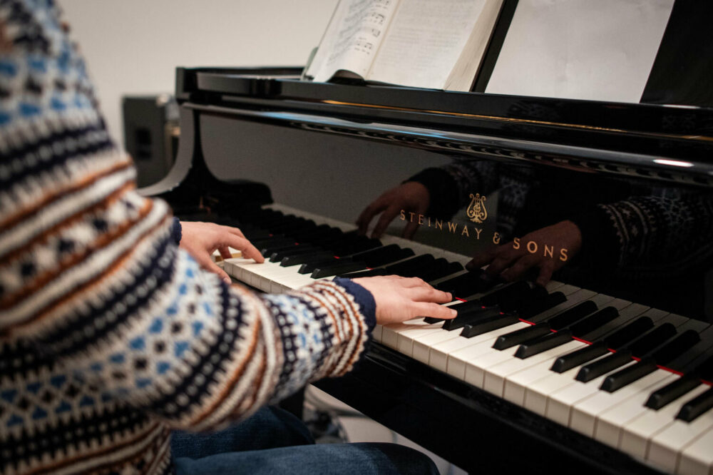 Foto: Ungen kvinnehender som spiller på tangente på et svart piano.
