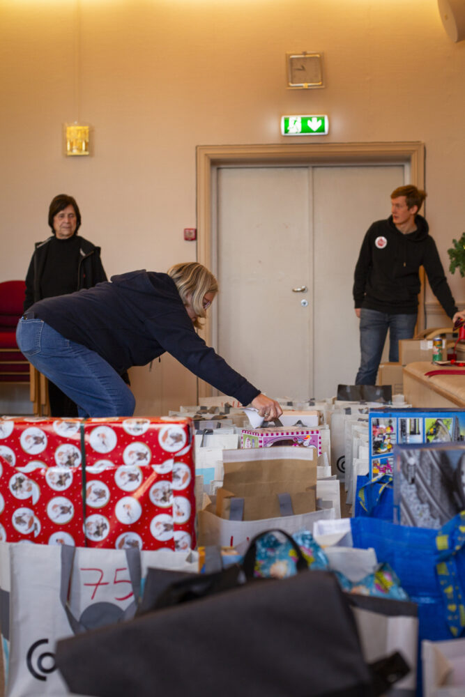Foto: Tre kvinner står i enden av et rom. De flytter rundt på gaver.