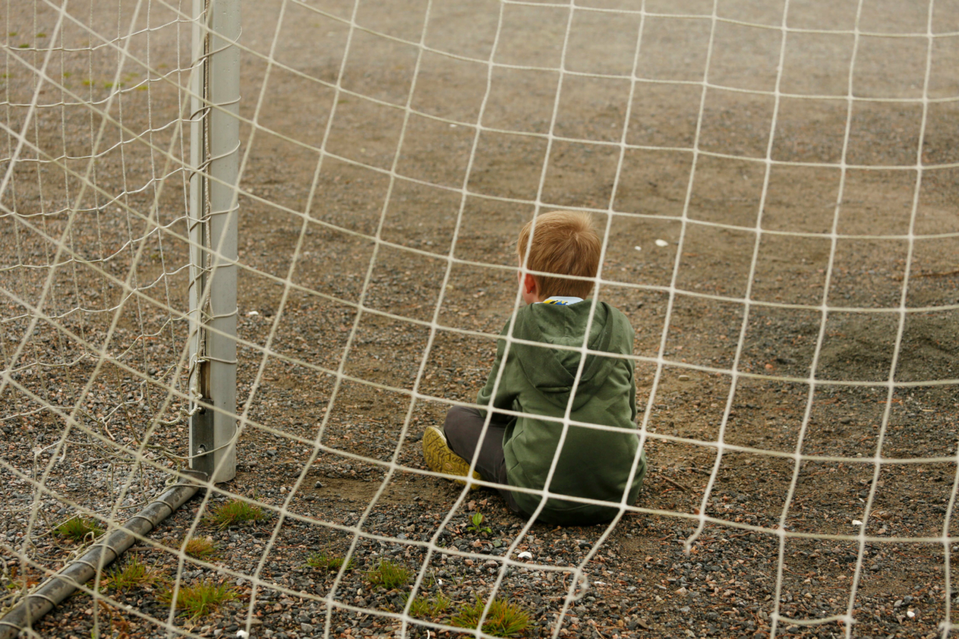 Foto: Gutt på rundt ti år sitter med ryggen til alene i et stort fotballmål. Ingen å leke med.