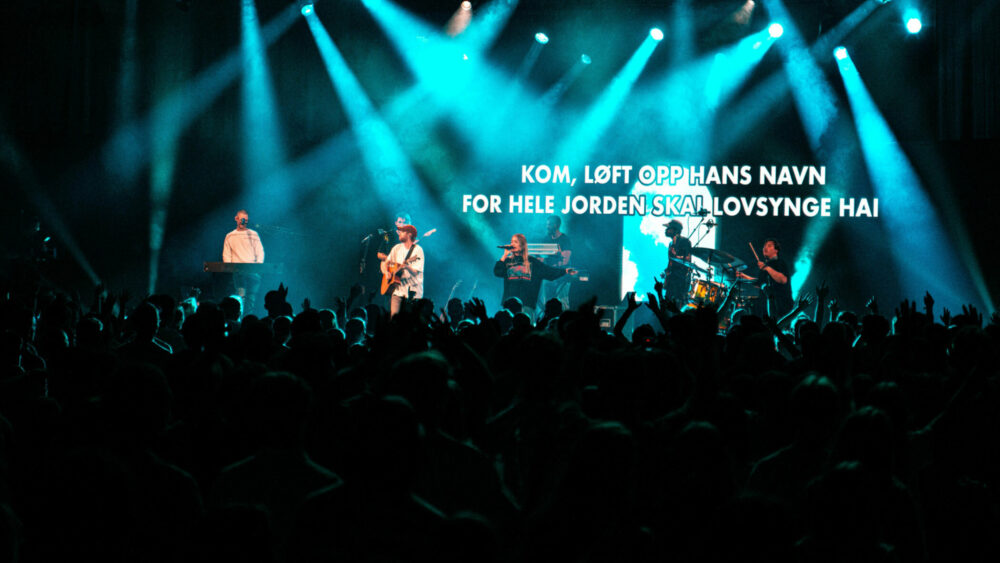 Foto: Fra en scene som bader i blått lys. Der spiller et band.