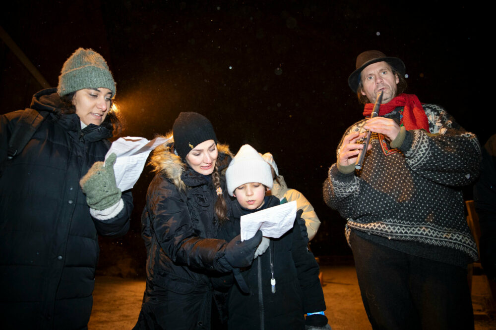 Foto: To kvinner, en gutt og en mann står på rekke. Kvinnene holder ark som det synges fra.