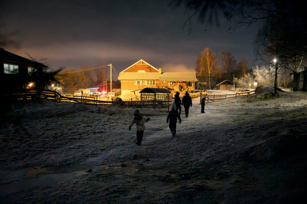 Foto: Fem-seks unger som leker på et gårdstun i mørket.
