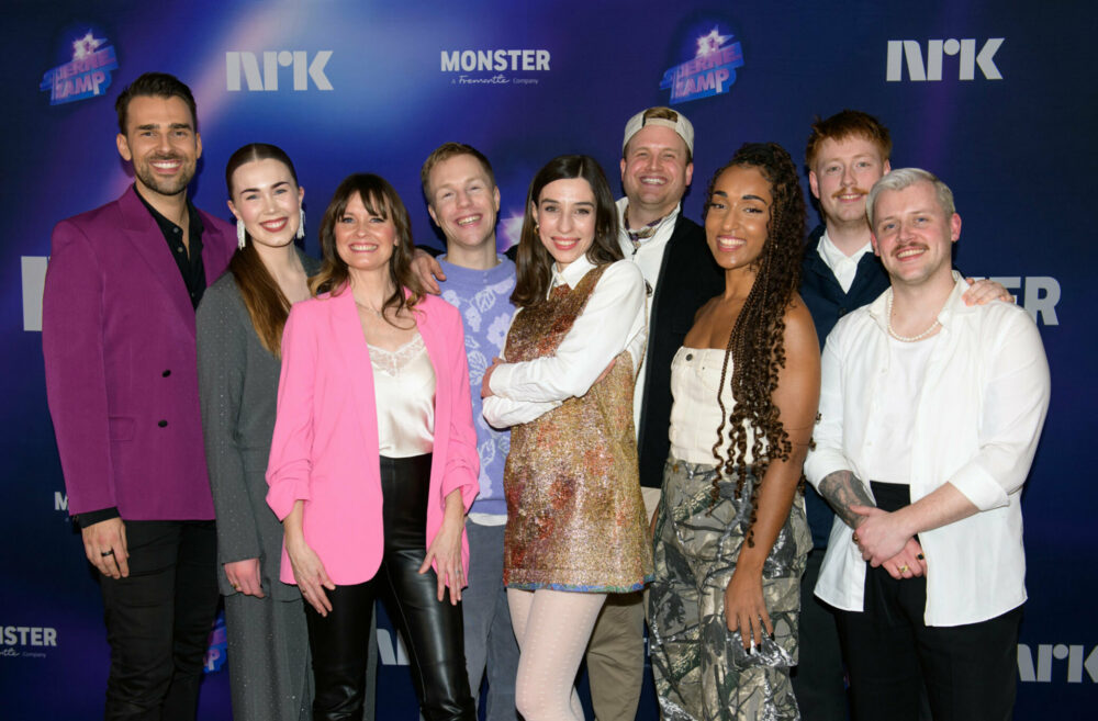 Foto: Gruppebilde med fem menn og fire kvinner foran en vegg med logoene til NRK, "Stjernekamp" og Monster. De smiler og har på seg sceneantrekk.