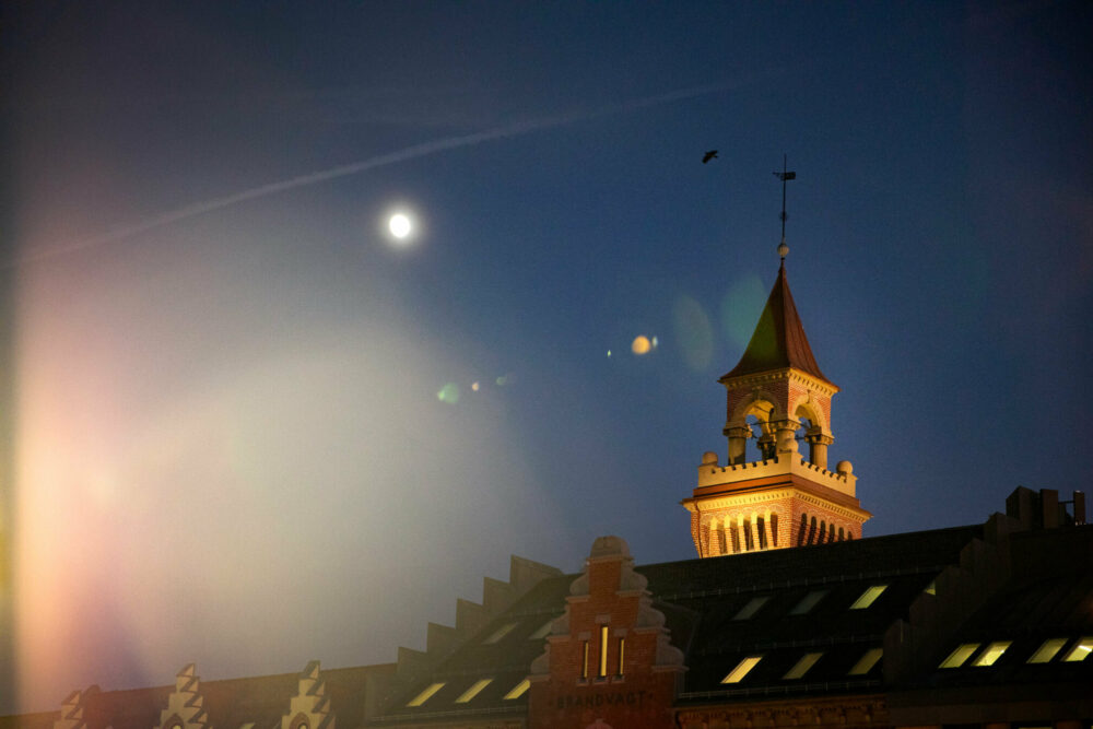 Foto: Et gammelt, opplyst tårn i mørk vinternatt.