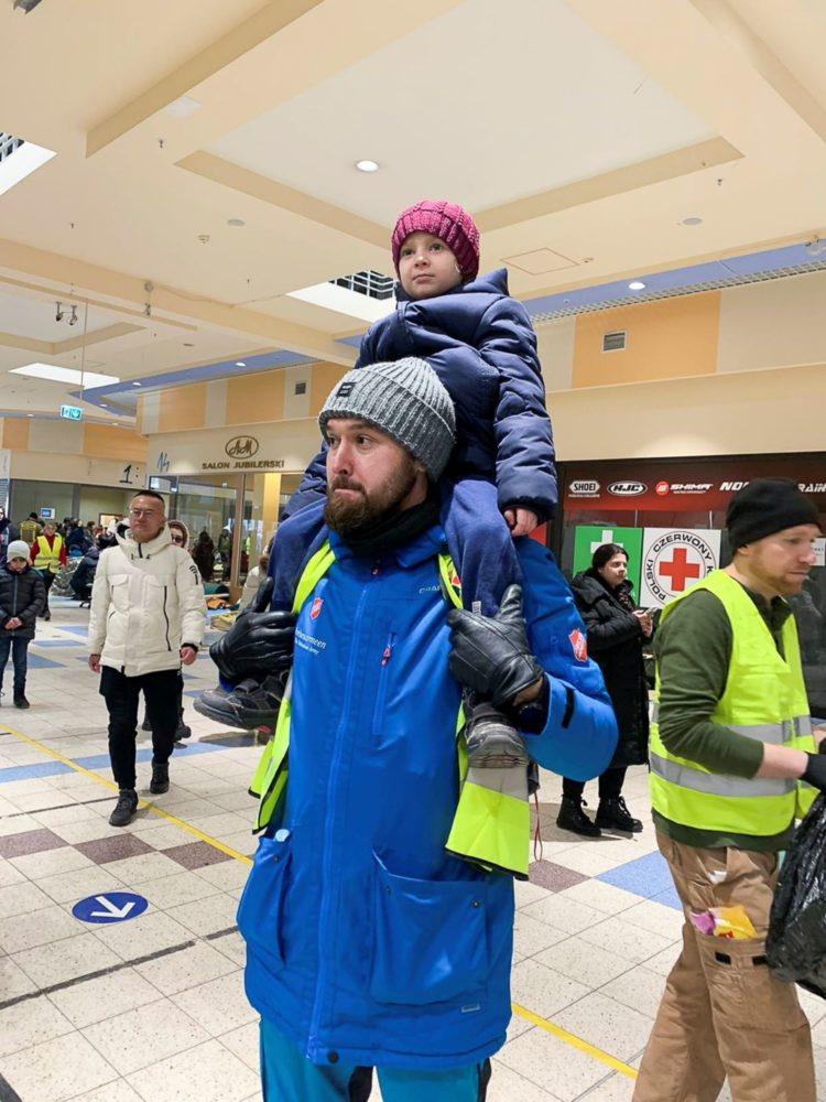 En frivillig hjelper til med barna i det overfylte lageret i Polen der flyktningene huses