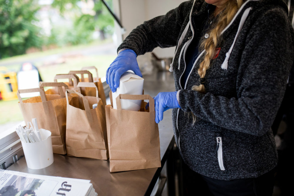 Bildet er et nærbilde av en rekke grå poser klare til utdeling inne i food trucken.
