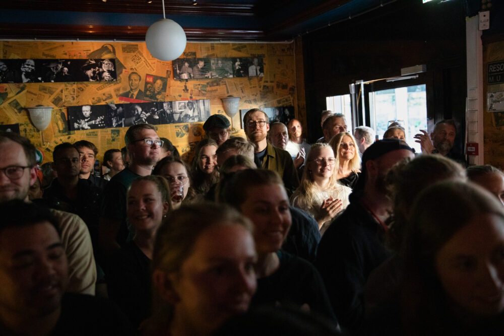 Folkemasse inne i publokalet. De står tett sammen.