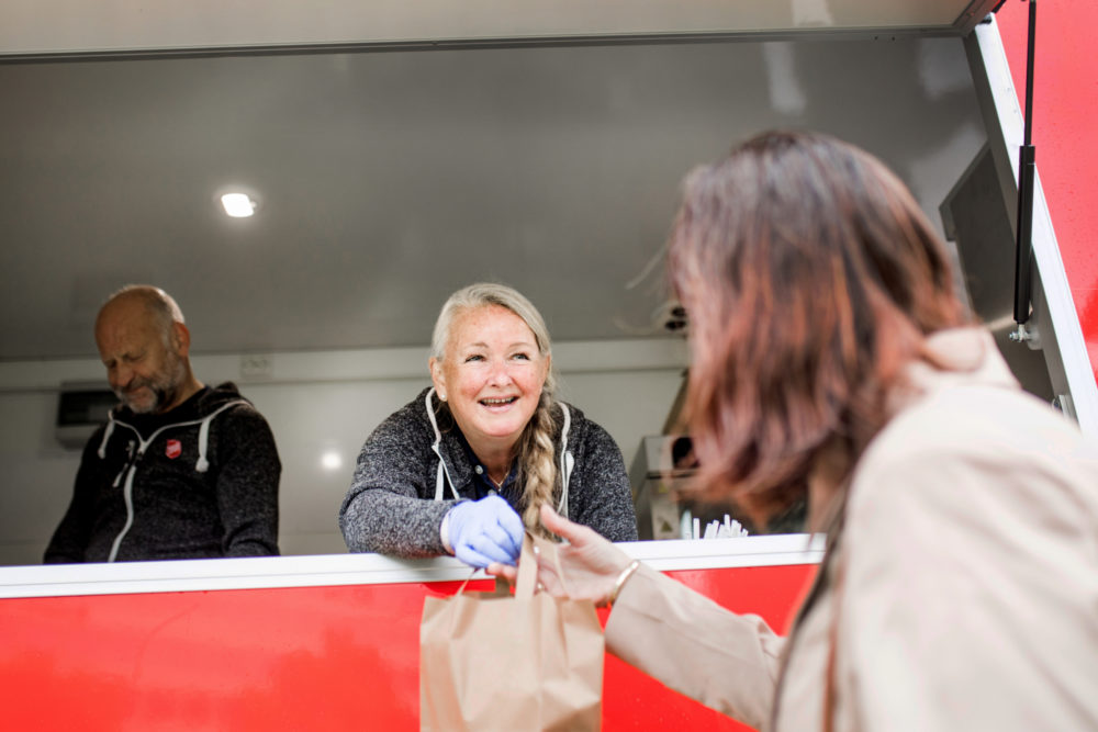 Frivillig på Fyrlyset Maj Britt Andersen deler ut mat via foodtruck under koronapandemien.