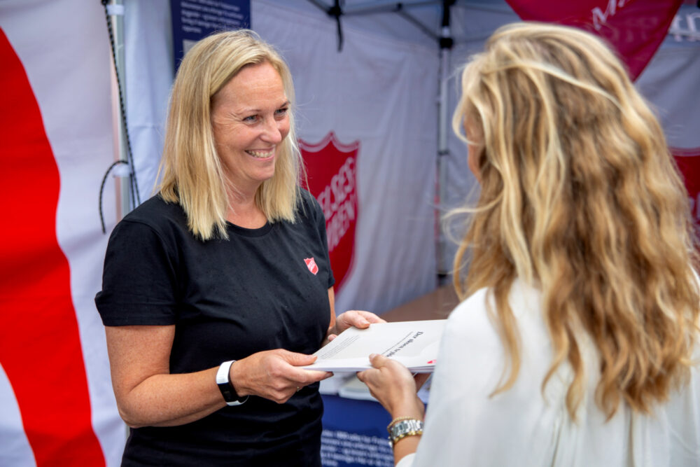 Foto: Blond kvinne deler ut rapport til en annen kvinne.