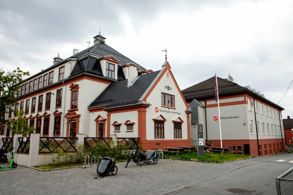 Foto: Eksteriør av stort, gammelt murbygg malt i beige og lakeserødt.