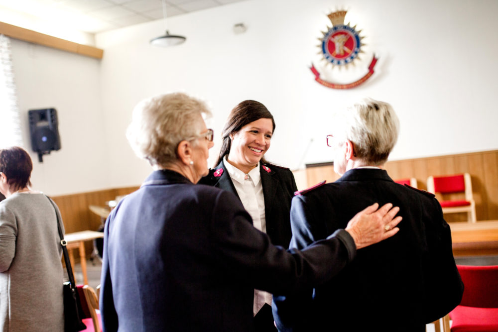 Damer i møtelokale i Frelsesarméuniform, smilende